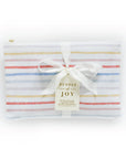 Elegantly packaged 'Bundle of Joy' gift set from The Everyday Mother, featuring a multi-colored striped baby journal enclosed in a clear case with a white satin ribbon bow. A tag attached to the bow describes it as a thoughtful, beautifully designed gift for new parents, emphasizing the practical and caring touch of a NICU mom. This set is ideal for tracking the early days and milestones of a newborn.